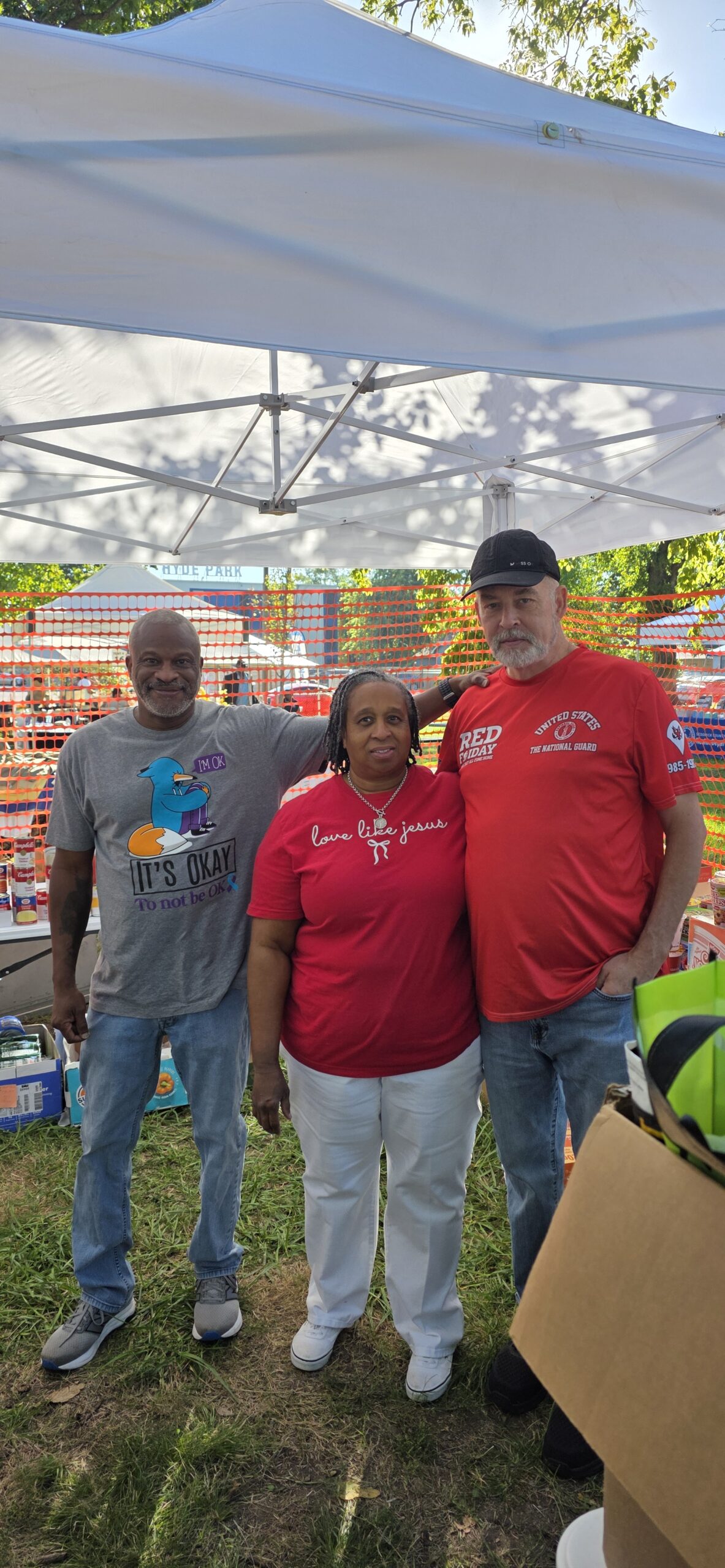 Three people together beneath a canopy at a community event